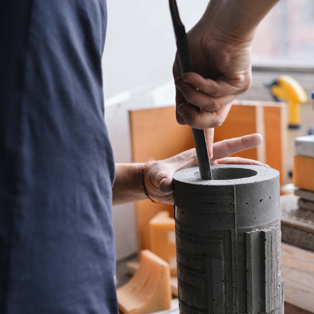 polishing a concrete vase with a file